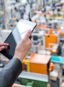 Close-up of someone using a tablet on a manufacturing floor.