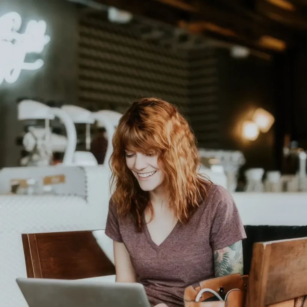 Woman smiling, working on a laptop at her desk.